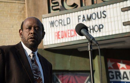 Costume design by Anette Cseri for the film Burden: Forest Whitaker speaking at a microphone outside a shopfront